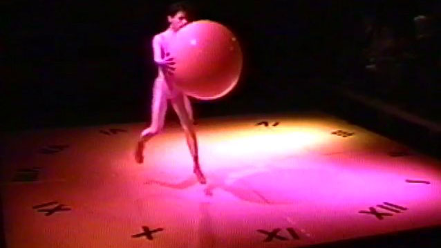 A dancer in mid-air holds a large ball.