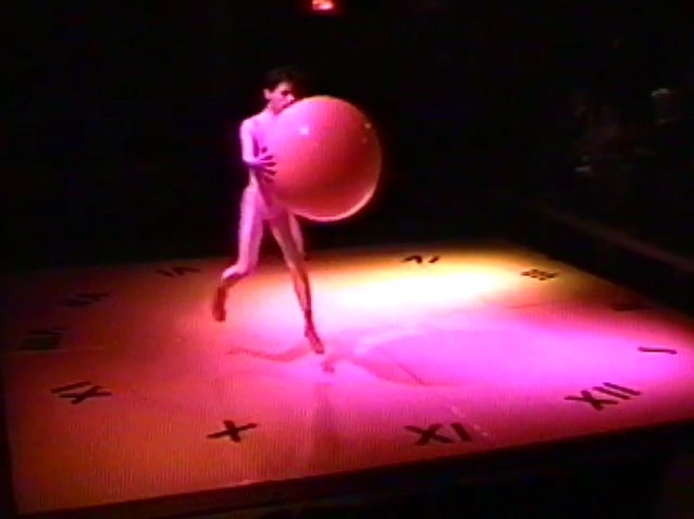 A dancer in mid-air holds a large ball.